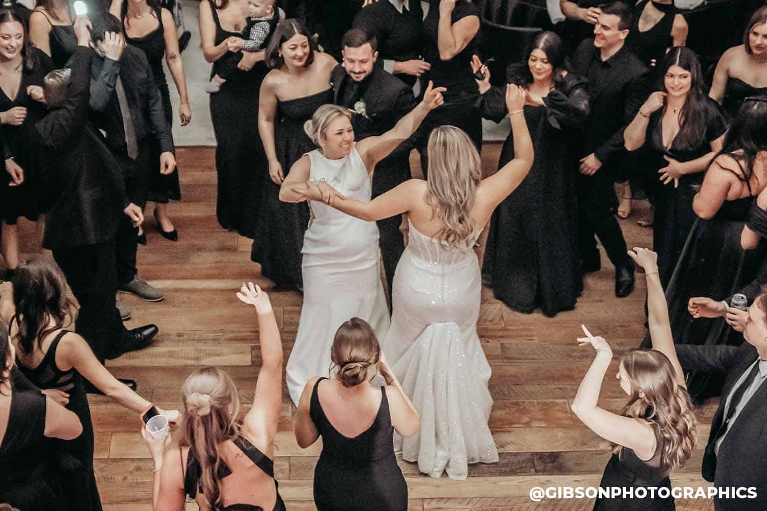Wedding reception dance floor with two brides in white dresses dancing together while dj axcess performs at white willow meadows